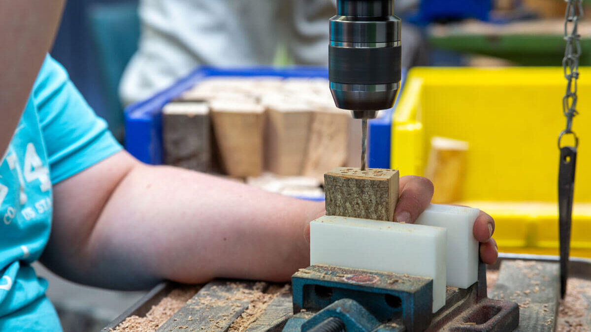 zu sehen ist eine Person bei Holzbohr arbeiten